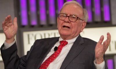 Warren Buffett holding an Apple or Amazon logo